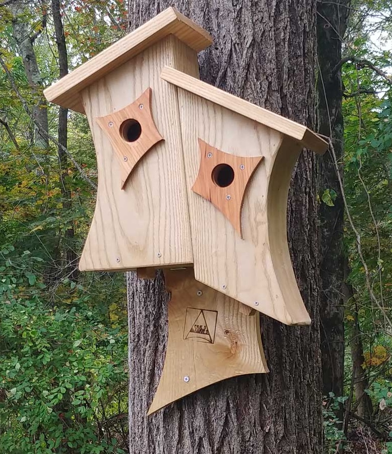 A duo of curved, wooden birdhouses make up one Duplex Nesting Box style aviary.