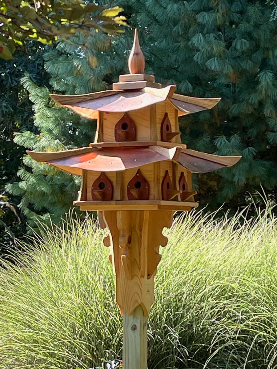 A wooden, Pagoda style birdhouse basking in the afternoon sun.